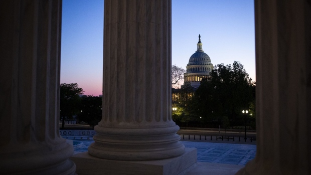 The U.S. Capitol stands past columns of the U.S. Supreme Court at dusk in Washington, D.C., U.S., on Thursday, April 16, 2020. President Donald Trump threatened Wednesday to try to force both houses of Congress to adjourn -- an unprecedented move that would likely raise a constitutional challenge -- so that he can make appointments to government jobs without Senate approval. Photographer: Al Drago/Bloomberg