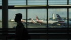 A traveler wearing a protective mask walks through an airport. Photographer: Sandy Huffaker/Bloomberg