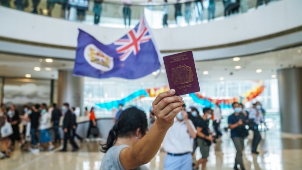 A demonstrator shows a British National (Overseas) passport as another waves a colonial-era Hong Kong flag during a lunchtime protest at the International Finance Center (IFC) shopping mall in Hong Kong, China, on Friday, May 29, 2020. Hong Kong leader Carrie Lam issued a letter to the city's people asking them to understand and support national security legislation that has sparked the biggest protests since last year and fresh concerns about future autonomy from China.