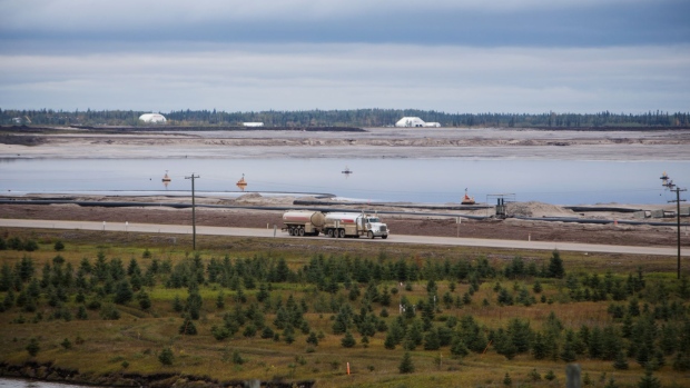 A truck drives past a tailings pond at the Syncrude Canada Ltd. facility in the Athabasca oil sands near Fort McMurray, Alberta, Canada, on Sunday, Sept. 9, 2018. New technologies such as driverless trucks and froth-treatments that eliminate the need for multibillion-dollar upgraders -- along with U.S. benchmark crude prices closer to $70 -- are helping make the industry profitable again.