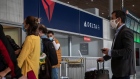 Travelers wearing protective face masks queue at a Delta customer service desk. Photographer: Adrienne Surprenant/Bloomberg