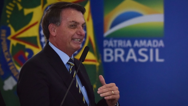 Jair Bolsonaro, Brazil's president, greets supporters following the National Flag Raising ceremony at Alvorada Palace in Brasilia, Brazil, on Tuesday, May 12, 2020. Bolsonaro got into another confrontation with state governors and Brazil's top court by adding gyms, beauty salons and barbershops to the list of activities that should remain open during the coronavirus crisis.