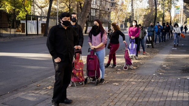 People wearing protective masks stand in line to enter a store in the city center of Santiago, Chile, on Saturday, June 13, 2020. Chile’s health minister resigned Saturday as daily coronavirus deaths reached a record, with infections moving from the wealthier areas of Santiago to the poorer neighborhoods where the country's lockdown had little effect.