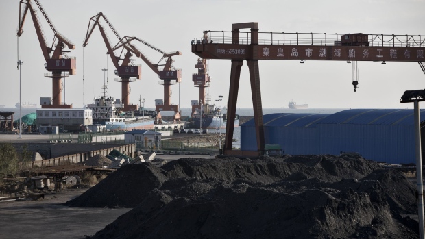 Piles of coal sit near port facilities as gantry cranes stand in the background at the Qinhuangdao Port in Qinhuangdao, China, on Friday, Oct. 28, 2016. China's efforts to quell surging coal prices showed signs they’re working, with benchmark prices dropping for the first time in a year as the country's production rose to the highest in seven months.