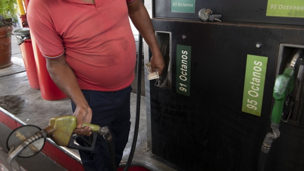 A worker wearing a protective mask refuels a vehicle at a Petroleos de Venezuela SA (PDVSA) gas station in Caracas, Venezuela, on Saturday, April 25, 2020. In a week when oil futures fell below zero, everyday Venezuelans are paying more than ever for gasoline, about $10 per gallon, as extreme shortages fuel a booming black market. Photographer: Carlos Becerra/Bloomberg