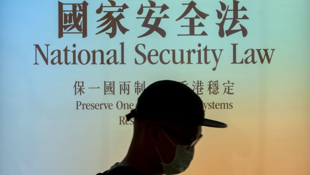 A pedestrian wearing a protective mask walks past a government-sponsored advertisement promoting a new national security law in Hong Kong, China, on Monday, June 29, 2020. The national security law that China could impose on Hong Kong as early as this week won't need to be used if the financial hub's residents avoid crossing certain "red lines," according to Bernard Chan, a top adviser to Hong Kong Chief Executive Carrie Lam.