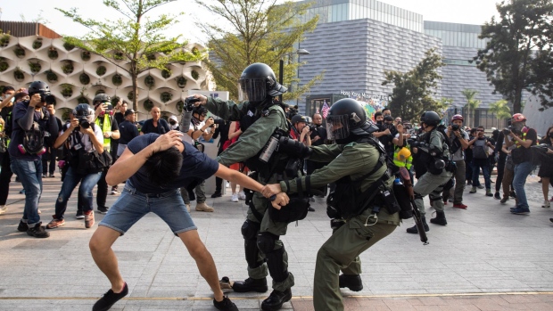 Riot police attempt to apprehend and arrest a demonstrator during a protest in the Tsim Sha Tsui district of Hong Kong, China, on Sunday, Oct. 27, 2019. Hong Kong pro-democracy activists demonstrated for the 21st straight weekend as unrest spreads around the globe, from South America to Europe, to the Middle East. Photographer: Kyle Lam/Bloomberg