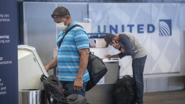A traveler wearing a protective mask uses a kiosk to check-in at a United Airlines Holdings Inc. counter at San Francisco International Airport (SFO) in San Francisco, California, U.S., on Wednesday, July 1, 2020. United Airlines Holdings Inc. plans to boost its domestic schedule for August to 48% of last years level, from 30% in July, offering another sign of rebounding travel demand.