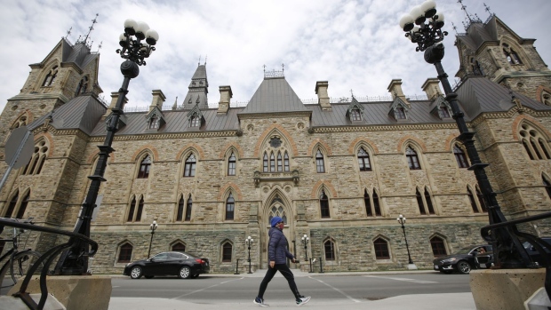 A pedestrian wearing a protective mask walks past the entrance of West Block on Parliament Hill in Ottawa, Ontario, Canada, on Wednesday, April 29, 2020.
