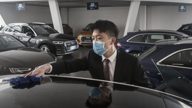 An employee wearing a protective mask wipes a vehicle on display inside an Audi AG dealership in Wuhan, Hubei Province, China, on Monday, April 6, 2020. Across China, the world's biggest car market, vehicle sales have been picking up since early February, albeit from almost zero.