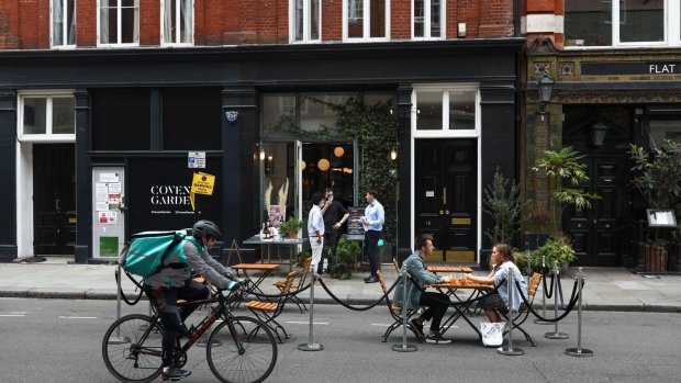 Customers eat and drink outside a seafood restaurant in the Covent Garden district of London, U.K., on Thursday, June 11, 2020. Shaftesbury Plc, the landlord that owns chunks of London's trendy Soho district has written down the value of its portfolio by more than 300 million pounds ($383 million), after the coronavirus pandemic forced its stores and restaurants to close. Photographer: Chris J. Ratcliffe/Bloomberg