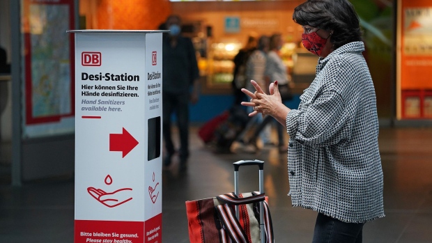 BERLIN, GERMANY - JULY 07: A traveller disinfects her hands at a disinfectant station offered by German state rail carrier Deutsche Bahn at Hauptbahnhof main railway station during the coronavirus pandemic on July 07, 2020 in Berlin, Germany. Deutsche Bahn is offering disinfectant and is distributing free protective face masks in an effort to encourage people to resume travel following the easing of lockdown measures in Germany. (Photo by Sean Gallup/Getty Images)