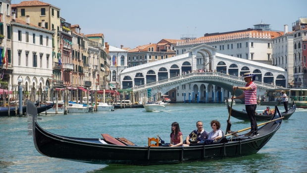 Tourists ride a gondolier on the Grand Canal in Venice. Photographer: Andrea Merola/Bloomberg