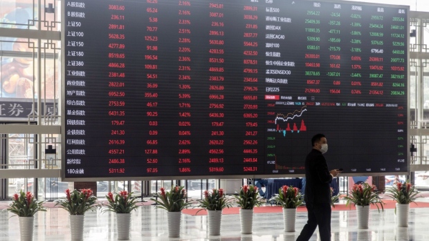 A man wearing a protective mask walks past an electronic stock board at the Shanghai Stock Exchange in Shanghai, China, on Monday, March 2, 2020. The pressure to get China back to work after the coronavirus shutdown is resurrecting an old temptation: doctoring data so it shows senior officials what they want to see. Photographer: Qilai Shen/Bloomberg