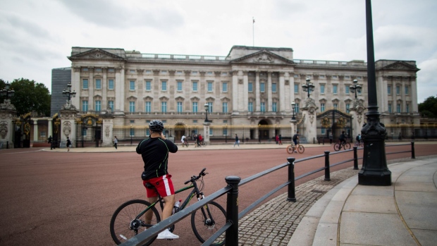 A cyclist takes a photograph of Buckingham Palace in London, U.K., on Friday, July 3, 2020. As the U.K. prepares to reopen pubs, restaurants and hotels on July 4, the government and businesses are counting on the economy getting a big boost on the path to recovery. Photographer: Chris Ratcliffe/Bloomberg
