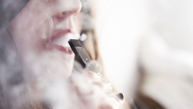 A person smokes a Juul Labs Inc. e-cigarette in this arranged photograph taken in the Brooklyn Borough of New York.