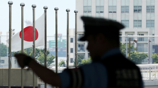 A police officer stands as a Japanese flag flies near the International Exhibition Center (INTEX) ahead of the 2019 Group of 20 (G-20) Summit in Osaka, Japan, on Saturday, June 22, 2019. Central bankers hand back the spotlight to presidents and prime ministers this week as leaders from the Group of 20 gather for a summit in Japan. Photographer: Buddhika Weerasinghe/Bloomberg