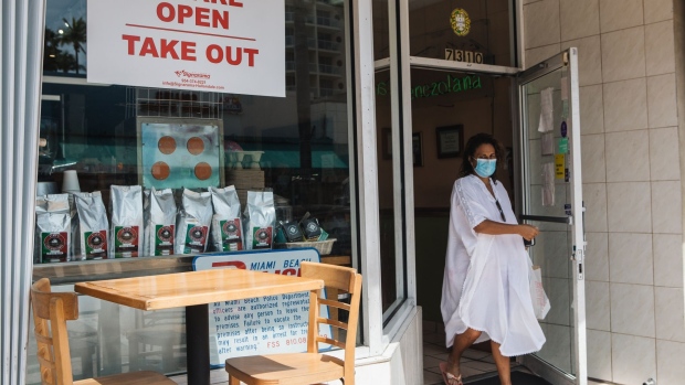 A customer wearing a protective mask exits a cafe in Miami. Photographer: Jayme Gershen/Bloomberg