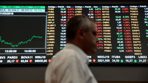 A person walks past an electronic board displaying stock activity at the Brasil Bolsa Balcao (B3) stock exchange in Sao Paulo, Brazil, on Thursday, March 21, 2019. Brazil's Ibovespa Index fell Thursday following the arrest of former Brazilian president Michel Temer as part of the Carwash corruption probe that's ensnared some of the country's top business executives and politicians. Photographer: Patricia Monteiro/Bloomberg