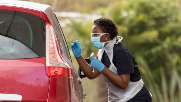 A medical worker, wearing a protective face mask and screen, disposable gloves and a plastic apron, takes a swap at a coronavirus drive-through testing center in the car park of the closed Chessington World of Adventures Resort theme park in Chessington, U.K., on Tuesday, March 31, 2020. Top officials now accept the country has not done enough to test the population and its key medical workers to be able to see how far the virus has spread -- and to stop it spreading further. Photographer: Jason Alden/Bloomberg