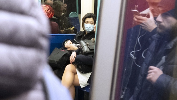 A passenger wears a protective face mask while sitting on the Docklands Light Railway (DLR) as it departs from Bank station in London, U.K., on Monday, March 2, 2020. U.K. Prime Minister Boris Johnson says “it is highly likely we will see a growing number of U.K. cases” in a press conference in London on Tuesday. Photographer: Bryn Colton/Bloomberg