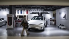 A man walks past a Tesla Model X electric vehicle, left, and a childrens' ride-on car sitting on display at a showroom in Hong Kong.