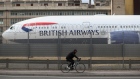 A cyclist passes a passenger aircraft, operated by British Airways. 