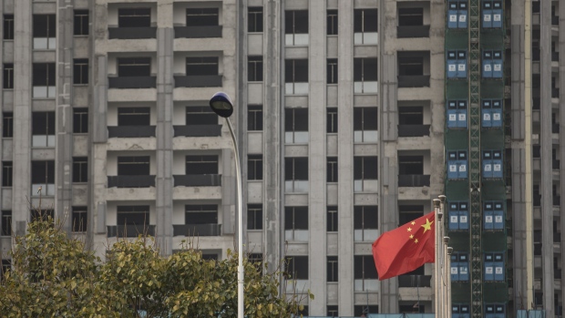 A Chinese flag flies in front of an unfinished building complex in Haikou, China, on Monday, March 12, 2018. Policy makers' pledges to support China's economy will help boost liquidity in the nation's capital markets, according to central bank adviser Ma Jun. Photographer: Qilai Shen/Bloomberg
