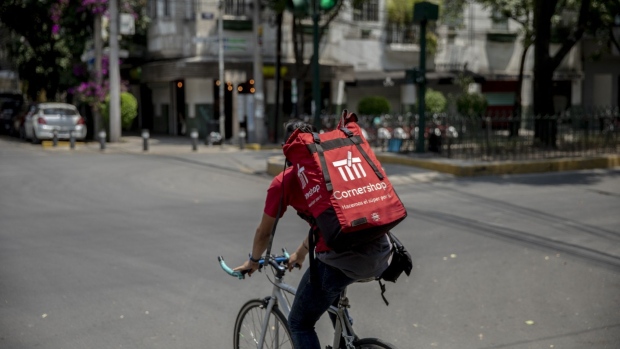 A worker rides a bicycle while making a Cornershop app delivery in Mexico City, Mexico, on Friday, April 3, 2020. As the coronavirus pandemic strangles economies and throws people out of work, food delivery drivers are competing for orders.