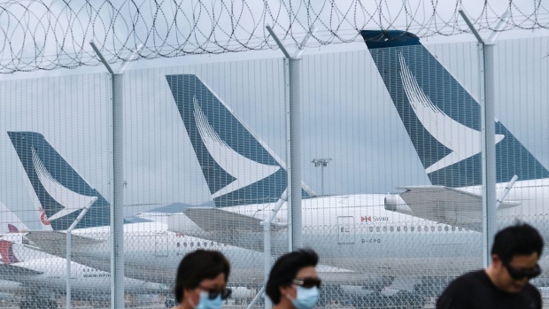 Aircraft operated by Cathay Pacific Airways Ltd. are seen through a barbed-wire fence as they stand parked on the tarmac at Hong Kong International Airport in Hong Kong, China, on Tuesday, June 9, 2020. Cathay became the latest global carrier to seek a lifeline in the aftermath of Covid-19 travel restrictions, outlining a plan to raise HK$39 billion ($5 billion) from the Hong Kong government and shareholders after months of warnings about the frailty of its business. Photographer: Roy Liu/Bloomberg
