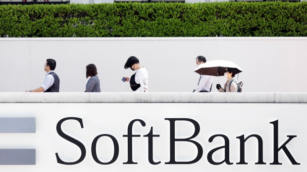 Pedestrians wearing protective masks walk past signage for SoftBank Corp. near a store in Tokyo, Japan, on Friday, May 15, 2020.