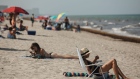 People sit and lay on the beach in Hollywood, Florida, U.S., on Thursday, June 25, 2020. On Thursday, Florida reported more than 5,000 new confirmed cases of COVID-19 in the state, reported the Associated Press.