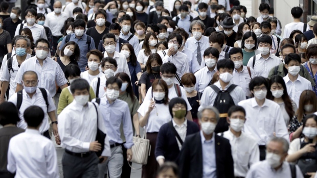 Pedestrians wearing protective masks walk along a street in the Shinjuku district of Tokyo, Japan, on Friday, July 10, 2020. Japan is forging ahead with further steps to re-open the economy even as daily coronavirus cases continue to climb, with local media reporting Tokyo posting a daily record of over 240 infections on Friday. Photographer: Kiyoshi Ota/Bloomberg