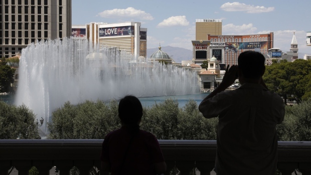 A couple takes photos of the fountain show at the Bellagio Hotel and Casino in Las Vegas, Nevada, U.S., on Thursday, June 4, 2020. All gaming venues in Nevada must follow strict protocols to account for Covid-19, including reduced capacity, more spacing on the casino floor and increased sanitation. Photographer: Joe Buglewicz/Bloomberg