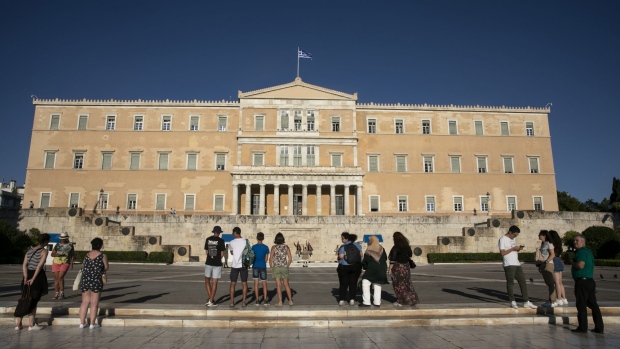 Tourists watch from a distance presidential guards performing a change of shift in Athens, Greece, on Wednesday, July 22, 2020. Tourism accounts for around a fifth of the Greek economy and more than a quarter of jobs. Photographer: Yorgos Karahalis/Bloomberg
