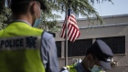 Police officers stand near an American flag flown in front of the U.S. Consulate General Chengdu 