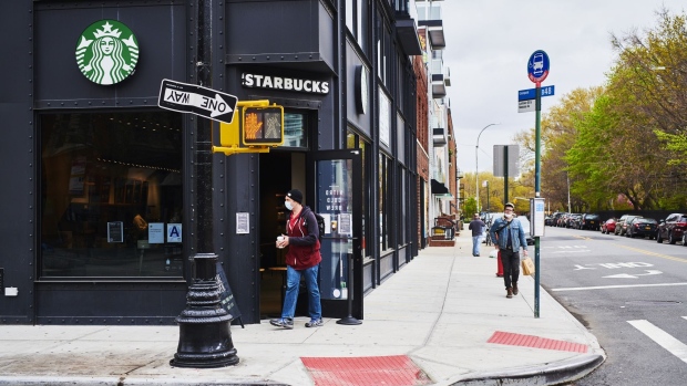 A customer wearing a protective mask orders outside of a Starbucks coffee shop in the Brooklyn borough of New York, U.S., on Monday, April 27, 2020. Starbucks Corp. is scheduled to release earnings figures on April 28.