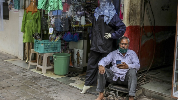 A man browses his mobile phone outside a clothes store in Mumbai, India, on Tuesday, July 14, 2020. With India now one of the world's top three Covid-19 hotspots, the country is focused on controlling its pandemic and reviving stalled economic growth, Prime Minister Narendra Modi said last Thursday.