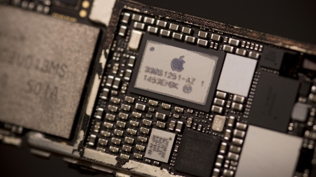 The Apple Inc logo is seen on the power management supply integrated circuit (IC) chip mounted in the logic board of an iPhone 6 smartphone in an arranged photograph in Bangkok, Thailand, on Saturday, Feb. 3, 2018. Apple Chief Executive Officer Tim Cook told shareholders on Feb. 13 at the company's annual meeting to expect higher dividends and stressed that succession planning is a priority.