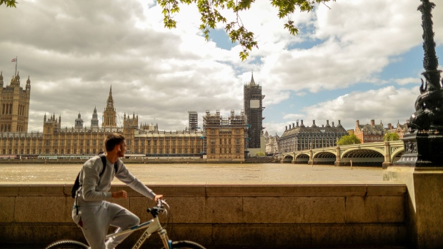 A cyclist travels along the Thames Path in view of the Houses of Parliament in London. Photographer: Jason Alden/Bloomberg