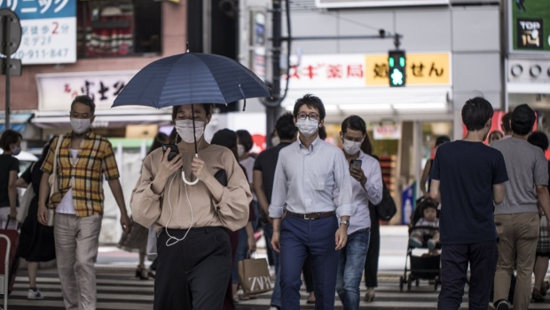Pedestrians wearing protective face masks cross a road in the Roppongi district of Tokyo, Japan, on Thursday, July 30, 2020. Officials in Japan are planning stricter measures on businesses and group activities as coronavirus cases continue to spread from a concentration around the capital to other urban areas across the country. Photographer: Shoko Takayasu/Bloomberg