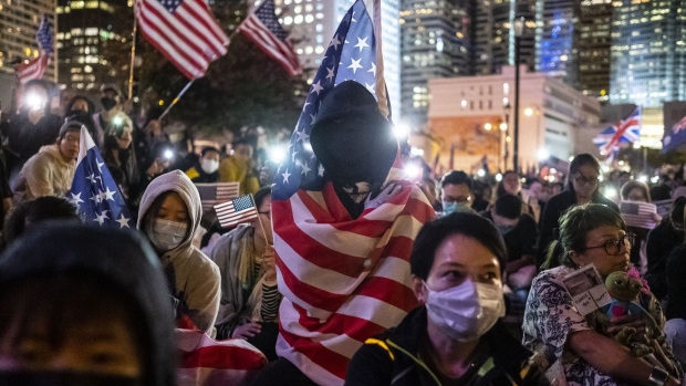 A demonstrator wrapped in a U.S. national flag sits with others during the "Thanksgiving Day Assembly for Hong Kong Human Rights and Democracy Act" at Edinburgh Place in the Central district of Hong Kong, China, on Thursday, Nov. 28, 2019. Donald Trump signed legislation expressing U.S. support for Hong Kong protesters, prompting China to threaten retaliation just as the two nations get close to signing a phase one trade deal. Photographer: Chan Long Hei/Bloomberg