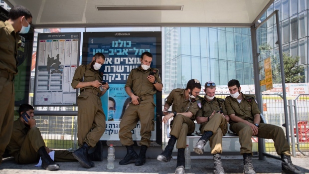 Israeli soldiers wearing protective face masks sit by a poster displaying coronavirus prevention measures in Tel Aviv, Israel, on Wednesday, July 22, 2020. Israel’s parliament gave the government sweeping authorities to combat a resurgent coronavirus outbreak, weakening its own oversight over cabinet decisions as Prime Minister Benjamin Netanyahu warns of a possible second lockdown.