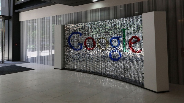A visitor passes a sign featuring Google Inc.'s logo inside their U.K. headquarters at Six St Pancras Square in London.