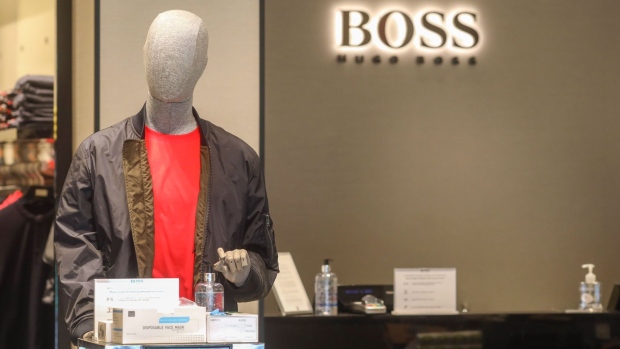 A mannequin stands next to a sanitizing station inside a Hugo Boss AG clothing store on Cheapside in the City of London, U.K., on Monday, June 15, 2020. British Prime Minister Boris Johnson encouraged consumers to go out and "shop with confidence" when stores reopen in England on Monday, as he suggested social distancing rules will be eased.