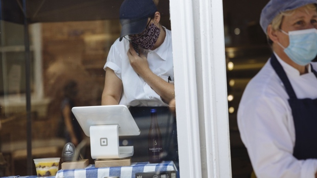 A worker wearing a protective mask uses a Square Inc. terminal inside a shop in Hudson, New York, U.S., on Sunday, June 28, 2020. As part of the phase 3 of reopening, the city of Hudson has implemented a "Shared Summer Streets" program that will allow businesses and pedestrians the space needed to operate with social distancing. Photographer: Angus Mordant/Bloomberg