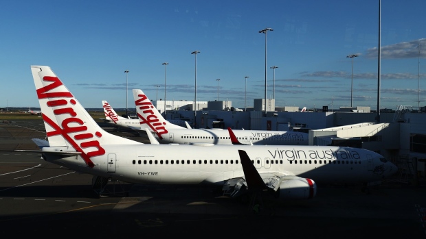 Aircraft operated by Virgin Australia Holdings Ltd. stand at gates at Sydney Airport in Sydney, Australia, on Friday, June 26, 2020. Bain Capital LP agreed to buy collapsed airline Virgin Australia in one of the biggest single bets on the industry since it was shattered by the coronavirus pandemic. Photographer: Brendon Thorne/Bloomberg