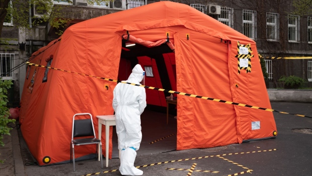 A medical worker wearing personal protective equipment (PPE) beside a tent set up for visitor temperature checks outside the Czerniakowski Hospital in Warsaw, Poland, on Wednesday, April 29, 2020. Poland plans to reopen shopping centers, hotels and kindergartens next week in the run-up to a presidential election scheduled for May 10.