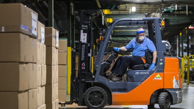 A worker wearing a protective face mask operates a forklift to move boxes at a facility in East Longmeadow, Massachusetts.