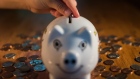 A coin is dropped into a piggy bank in this arranged photograph taken with a tilt-shift lens to illustrate the theme of risk in Oradell, New Jersey, U.S., on Thursday, June 18, 2015.